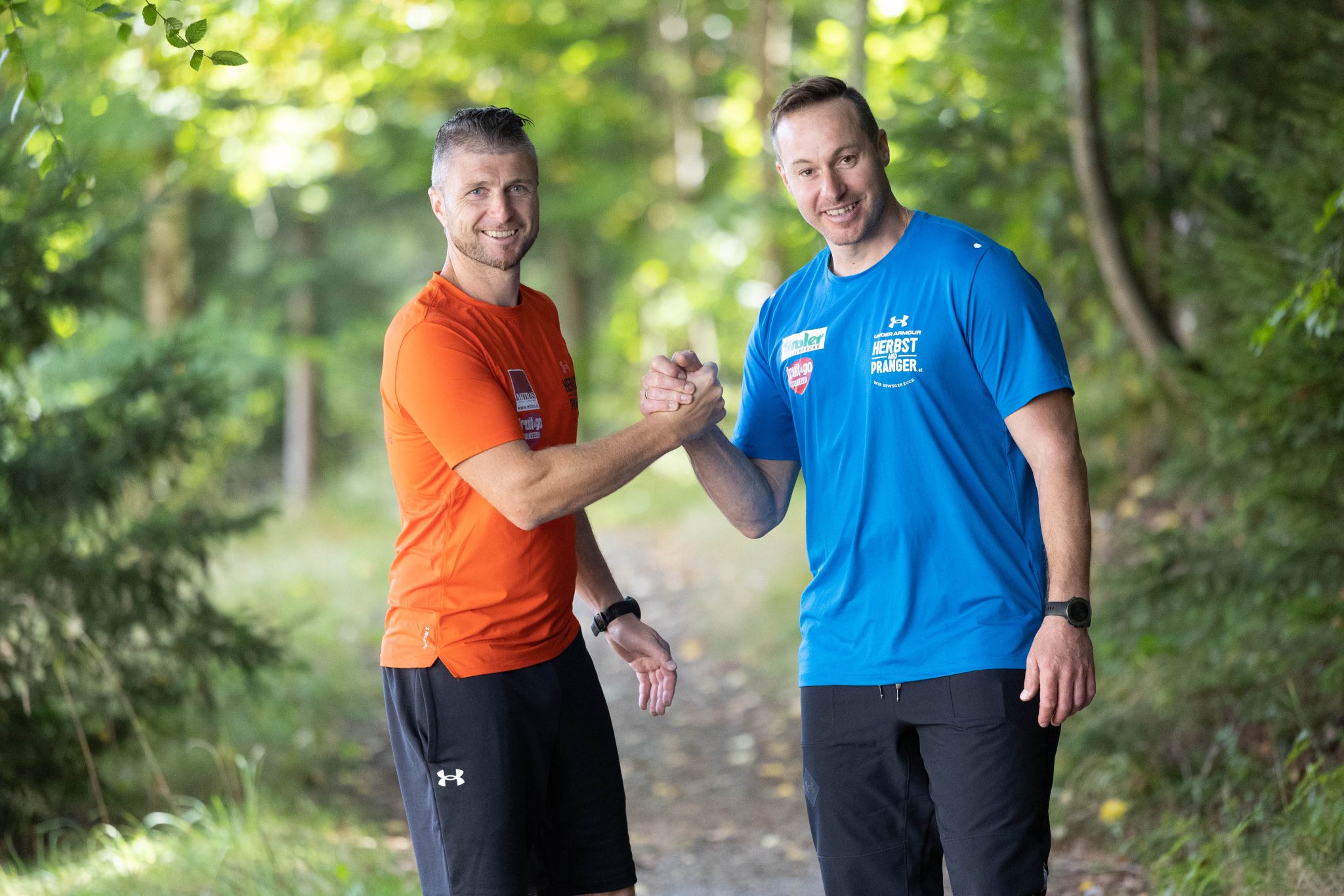 Reinfried Herbst und Manfred Pranger wie sie nebeneinander stehen und sich die Hand drücken. In der Natur.